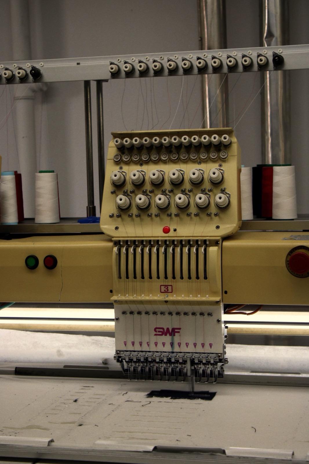 Détail d'une machine à broder industrielle avec bobines de fil
